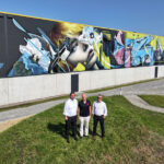 Den Gewerbecampus Delmenhorst ziert ein großflächiges Wandgemälde (Mural) des Künstlers Marcus Debie (Mitte), der unter dem Namen Gomad bekannt ist. Auf dem Foto ist er zusammen mit Simon Rickers (links) und Sven Mester zu sehen (beide von DLH).