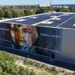 Das großformatige Mural „Erinnerung verpflichtet“ des international bekannten Künstlers Falk Lehmann alias Akut an der Außenhülle der Immobilie nimmt Bezug auf die Geschichte des Grundstücks: Auf dem Areal befand sich 1933 das nationalsozialistische Schutzhaftlager ‚Am Hochkreuz‘, in dem Menschen aus der Region inhaftiert und misshandelt wurden. Mit dem Mural wird diese Geschichte dauerhaft sichtbar in den Standort integriert. Das Motiv verbindet die Porträts von Anne Frank und Margot Friedländer und schlägt damit eine Brücke zwischen historischem Erinnern und heutiger Verantwortung.